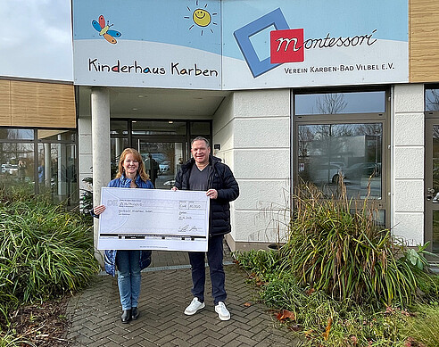 Stefan Kraft überreicht einen Spendenscheck an die ehrenamtliche Geschäftsführerin des Montessori Kinderhauses Karben